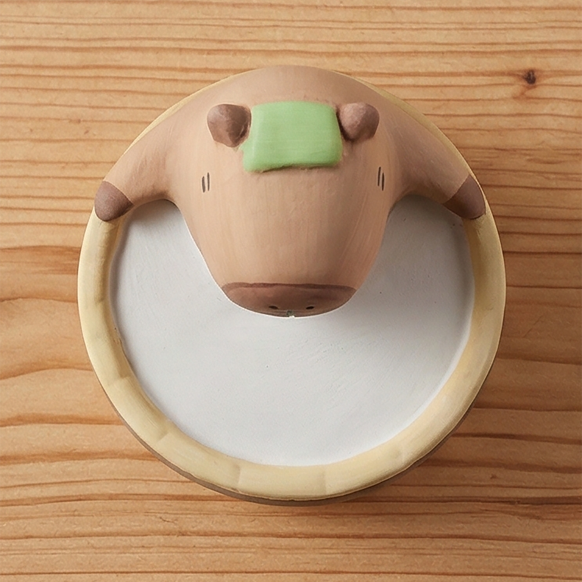 Yururi Biyori Aromafigur Capybara Draufsicht mit grünem Duftstein auf Holzoberfläche