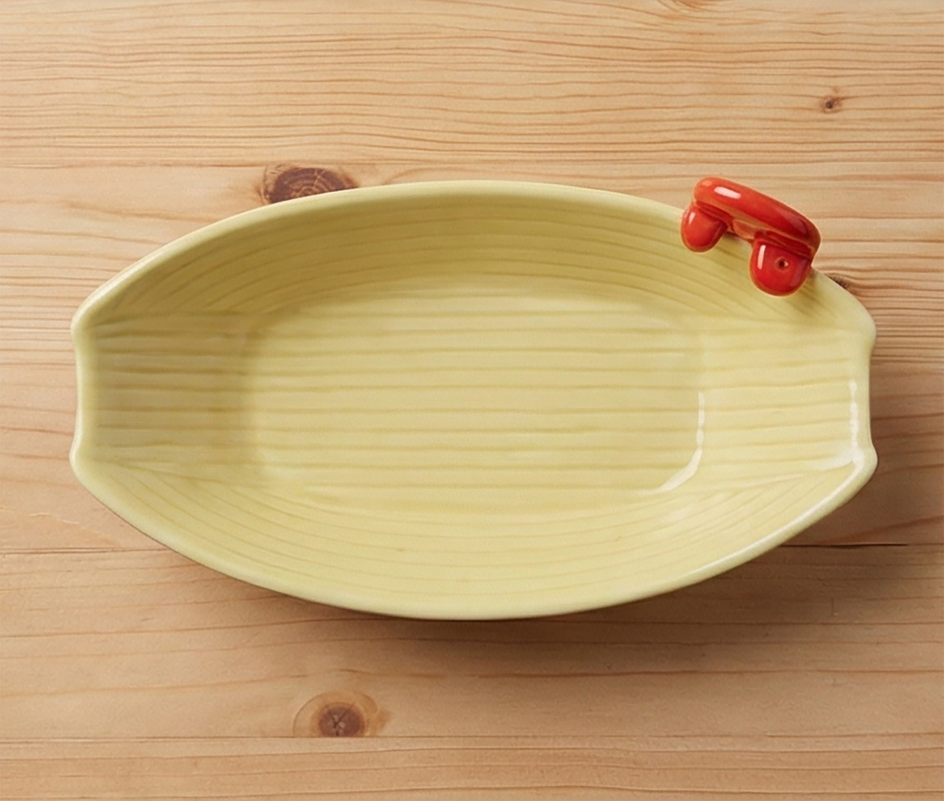 Draufsicht auf cremefarbene Takoyaki Schiffchen-Schale mit rotem Octopus-Griff