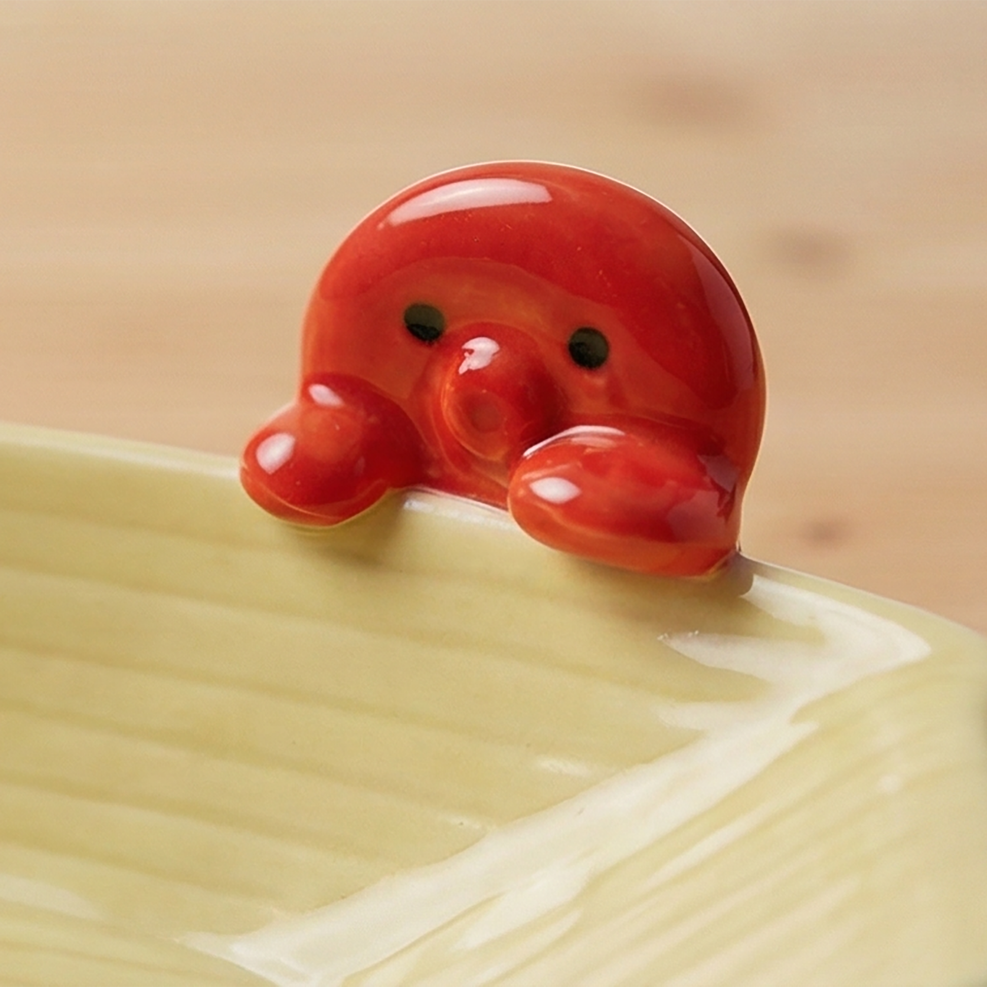 Nahaufnahme des roten Takoyaki-Octopus Griffs mit schwarzen Augen auf cremefarbener Schale