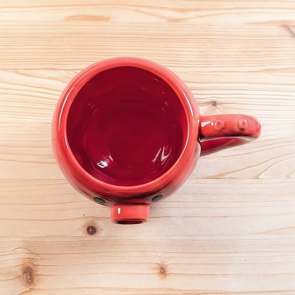 Ansicht von oben auf das rote Takoyaki-Octopus Teigkännchen auf Holzuntergrund mit sichtbarem Ausgießer an der Unterseite