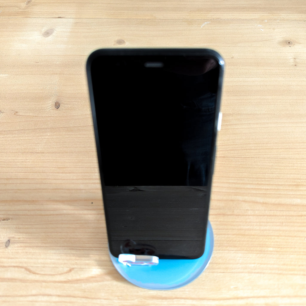 Rückansicht eines schwarzen Smartphones in dem blauen Acryl-Ständer mit Burgmotiv