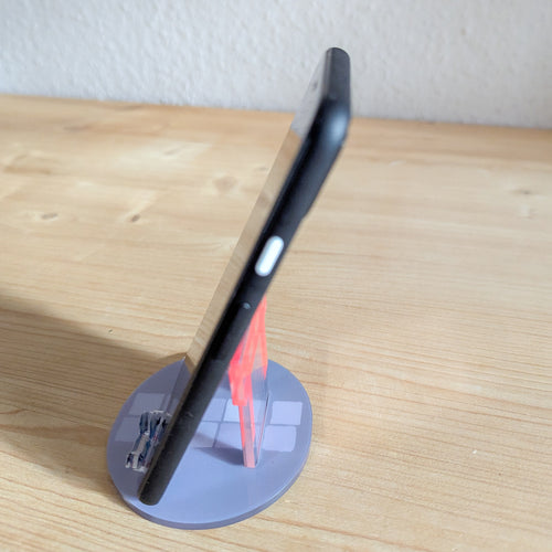 Schwarzes Smartphone auf dem roten Torii Smartphone-Ständer mit grauer Basis auf Holzuntergrund