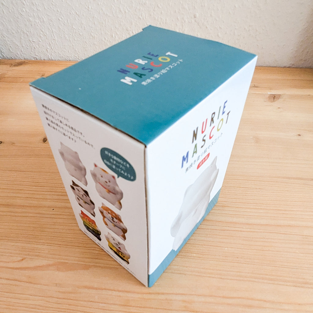 Nurie Mascot Bemalfigur Katze Verpackungsbox mit türkisfarbenem Deckel und verschiedenen Bemalmöglichkeiten der Glückskatze